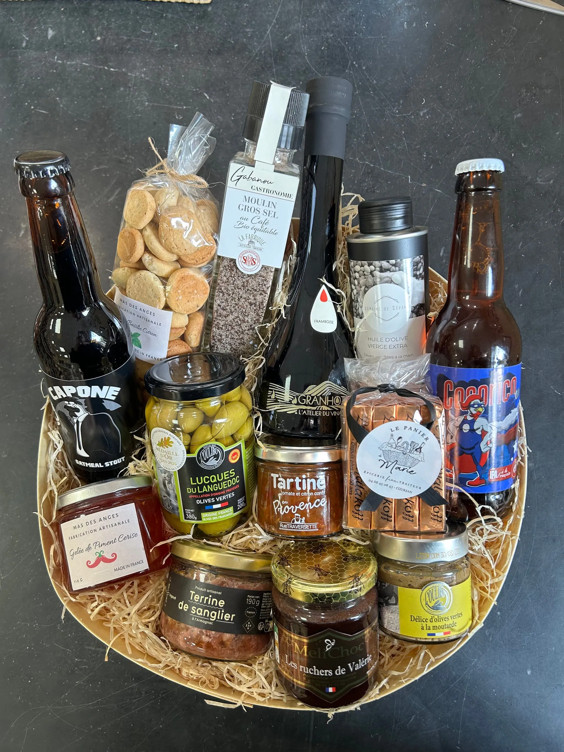 Panier gourmand garni de bières, d’olives, d’huile, de biscuits, de terrines et de miel