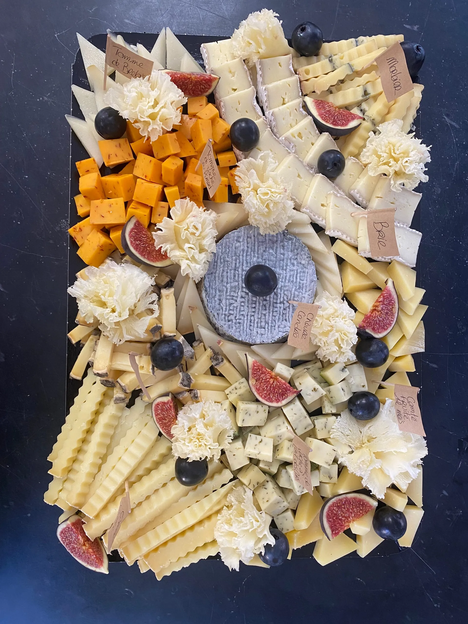 Plateau de fromages variés décoré de figues et de raisins